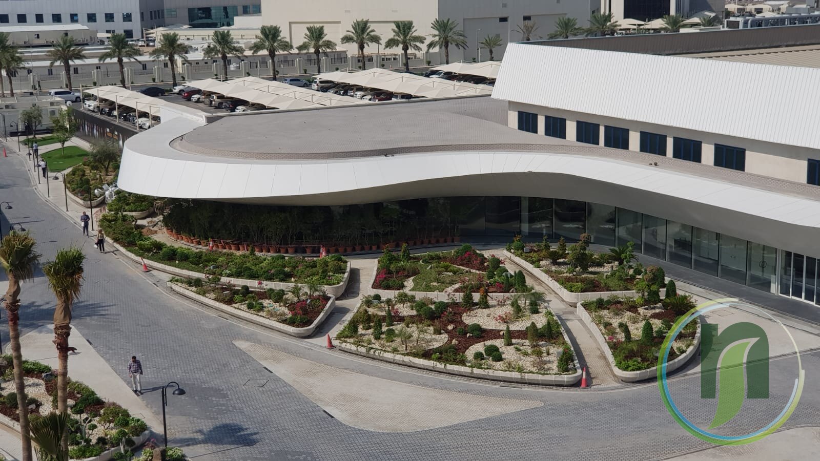Aerial view of landscaped planting beds in a paved courtyard around a modern building in Qatar