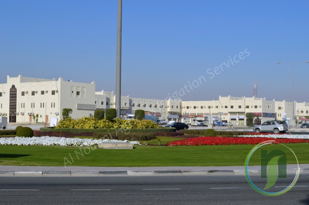 White building with a manicured lawn and red flower bed in Doha, Qatar